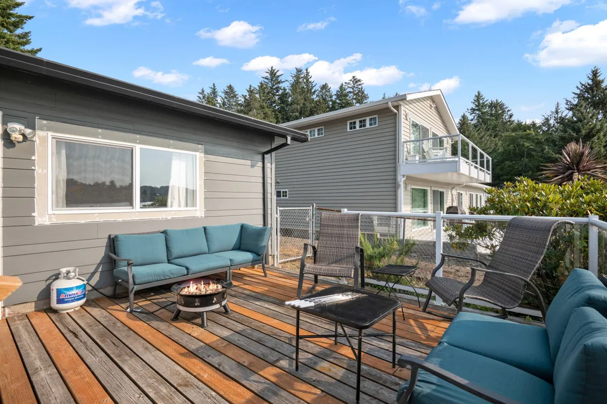 This exterior image shows a cozy outdoor fire pit surrounded by comfortable seating, set against a backdrop of greenery. The scene suggests an inviting spot to relax, listen to birdsong, or perhaps witness local wildlife at dusk, all while being enveloped by nature.
