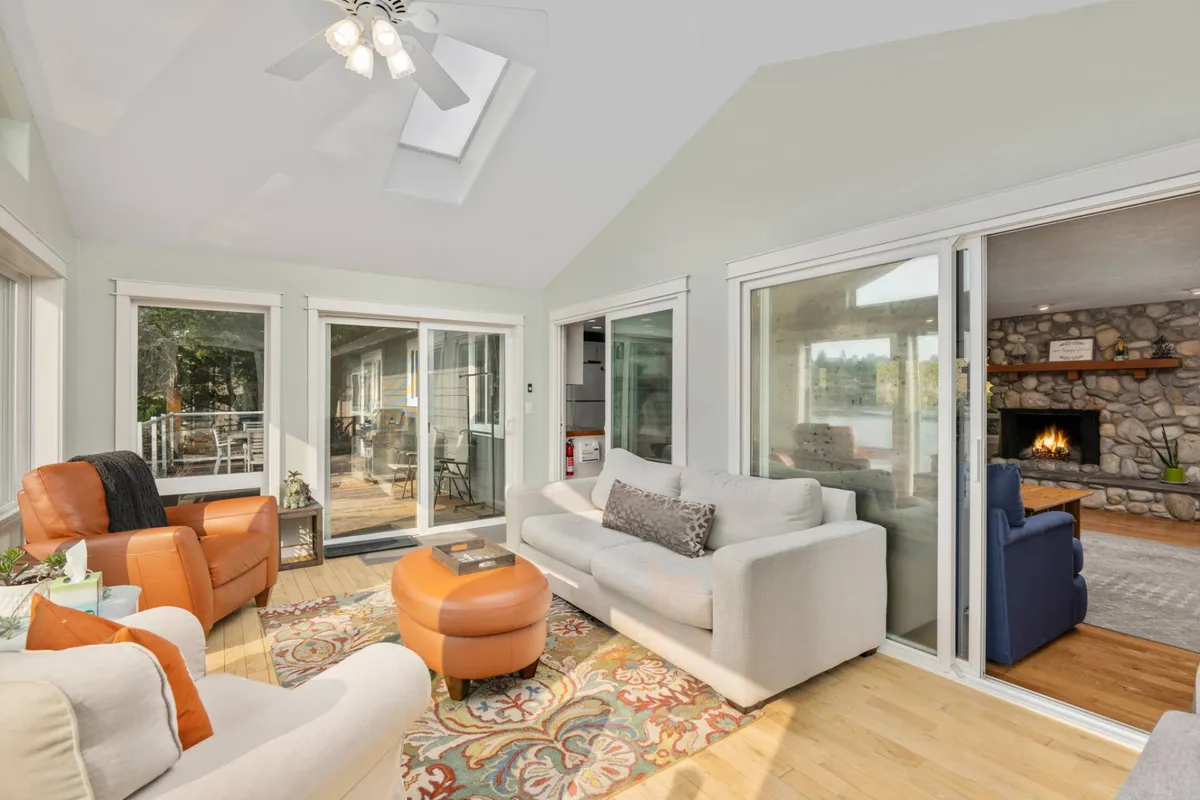 A bright, airy living room featuring a sofa, armchairs, a coffee table, and a fireplace, with large windows letting in natural light. The space feels cozy and welcoming—a perfect spot for morning coffee or evening relaxation, with enough room for pets to join the fun.
